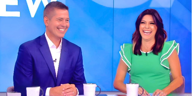 Sean Duffy wearing blue coat with white shirt, and his wife Rachel Campos wearing green top, smiling elegantly , with blue background