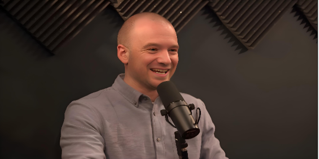 Sean Evans smiling and wearing dark color shirt ,standing in front of mic, depicting Sean Evans net worth