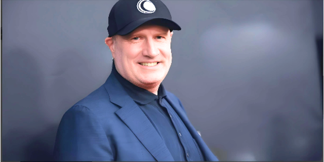 Kevin Feige wearing blue shirt and blue coat with mesmerizing smile on face, depicting Kevin Feige net worth